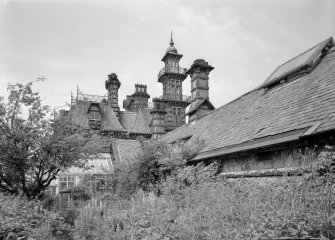 Detail of the back of Rockville, 3 Napier Road, Edinburgh showing the tower, conservatories, and outbuildings, in an overgrown garden.