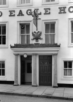 Detail of five window block's twin colonnaded doorways, double-headed eagle and hanging sign, Spread Eagle Hotel, 20 High Street, Jedburgh.