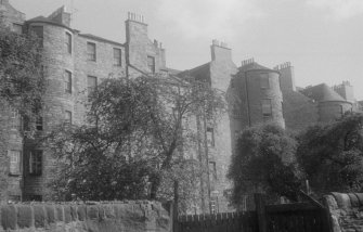 View of the rear of the south side of Buccleuch Place, Edinburgh, partially obscured by trees, seen from the south from Meadow Lane.