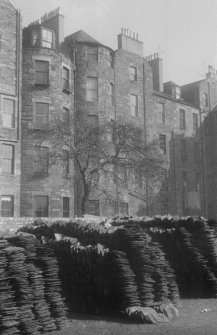 General view of the rear of the south side of Buccleuch Place, Edinburgh, seen from the south from Meadow Lane, with slates piled up in the foreground.