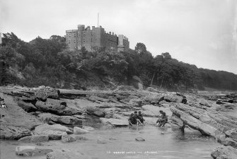 View of Wemyss Castle showing children paddling in sea