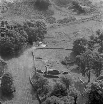 Oblique aerial view centred on the remains of St Blane's Church and burial ground, Bute, taken from the SE.