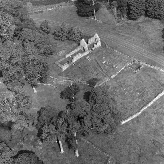 Oblique aerial view centred on the remains of St Blane's Church and burial ground, Bute, taken from the SW.
