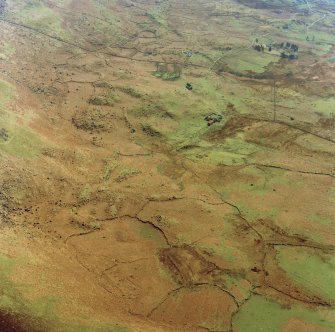 Oblique aerial view centred on the remains of the township and field-system with farmstead adjacent, taken from the NNE.