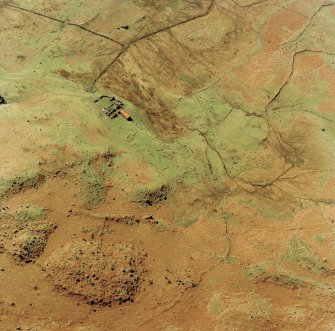 Oblique aerial view centred on the remains of the township and field-system with farmstead adjacent, taken from the NE.