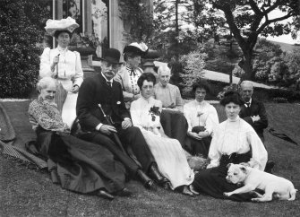 Copy of historic photograph showing group of people sitting in garden.