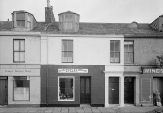 View of 7-11 Princes Street, Ardrossan, from SW, showing a general store and cycle shop.