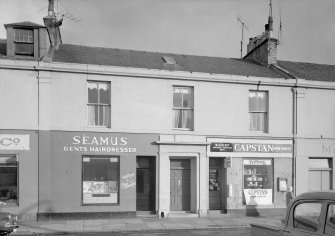View of 31-35 Princes Street, Ardrossan, from SW, showing Seamus Gents Hairdresser and a general store.