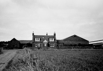 View of front elevation with farm buildings in the background