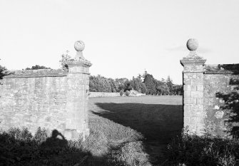 General view looking through gate piers, topped by ball finials, towards garden.