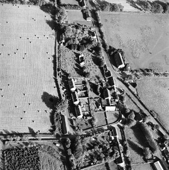 Oblique aerial view centred on the remains of the church and burial ground with old church and hotel adjacent, taken from the W.