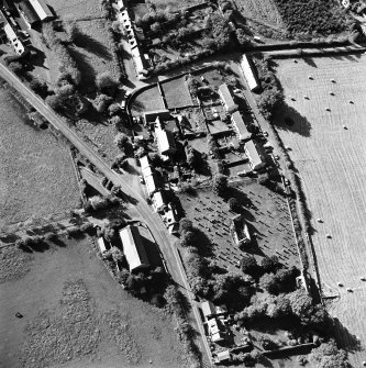 Oblique aerial view centred on the remains of the church and burial ground with old church and hotel adjacent, taken from the E.