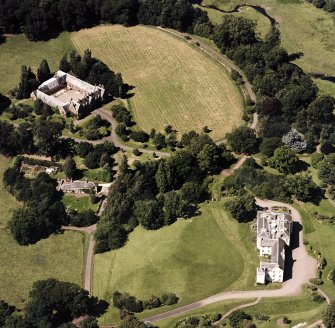 Oblique aerial view centred on the country house and stables, taken from the SE.