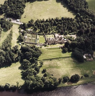 Oblique aerial view of Abbotsford centred on the country house with tea room, gardens and stables adjacent, taken from the NW.