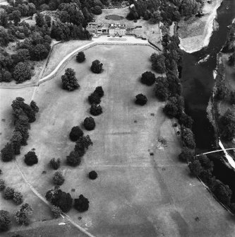 Oblique aerial view, taken from the WSW, centred on the country house, formal gardens and stables.