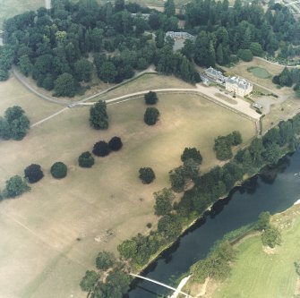 Oblique aerial view, taken from the SW, centred on the country house, formal gardens and stables.