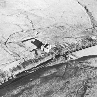 Oblique aerial view of Hermitage Castle centred on the remains of a castle, taken from the SW.