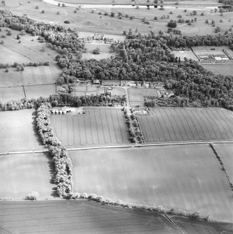 Oblique aerial view centred on the farmsteading, kennels and cottage with country house and formal garden adjacent, taken from the NW