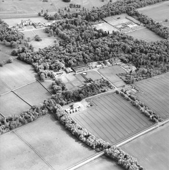 Oblique aerial view centred on the farmsteading, kennels and cottage with country house and formal garden adjacent, taken from the NNW