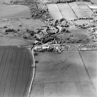 Oblique aerial view centred on the farmsteadings, church and burial ground with village adjacent, taken from the SE