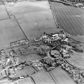 Oblique aerial view centred on the farmsteadings, church and burial ground with village adjacent, taken from the NNW