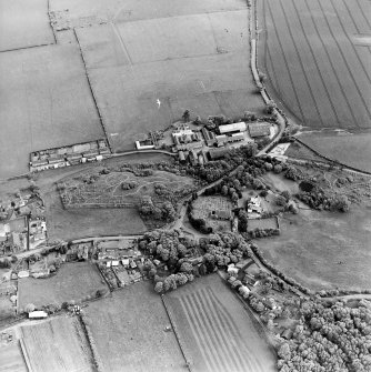 Oblique aerial view centred on the farmsteadings, church and burial ground with village adjacent, taken from the NW