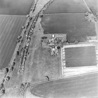 Oblique aerial view centred on the farmhouse and steading with the remains of the plantation adjacent , taken from the WSW