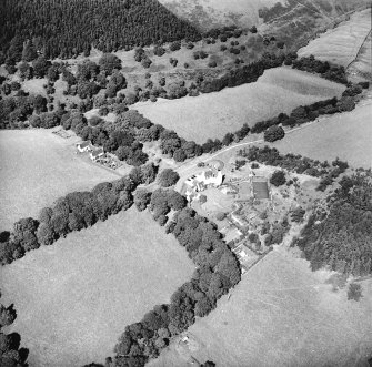 Oblique aerial view centred on the country house with the stables adjacent, taken from the S.