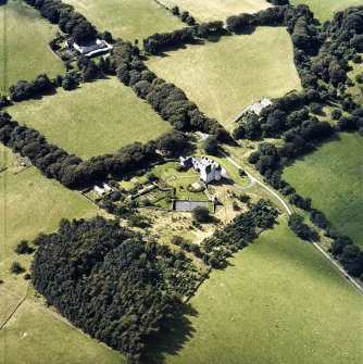 Oblique aerial view centred on the country house with the stables and farmsteading adjacent, taken from the E.