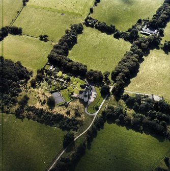 Oblique aerial view centred on the country house with the stables and farmsteading adjacent, taken from the NNE.
