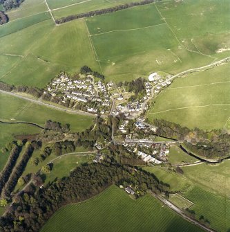 Oblique aerial view of Eddleston centred on the church and churchyard, taken from the W.