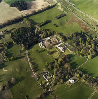 Oblique aerial view centred on the country house, stables and walled garden with the gate-lodge adjacent, taken from the SW.