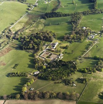 Oblique aerial view centred on the country house, stables and walled garden with the gate-lodge adjacent, taken from the NW.