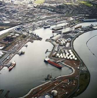 Oblique aerial view centred on the docks with the oil refinery and town adjacent, taken from the NNE.