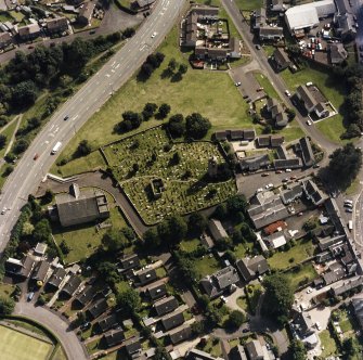 Oblique aerial view centred on the burial ground, belfry and clock tower with church and manse adjacent, taken from the N.