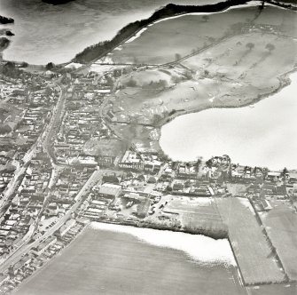 Oblique aerial view, taken from the NNW, centred on the S part of the town, with St Mary Magdalene's church and burial ground and Lochmaben old castle and motte visible in the centre of the photograph.