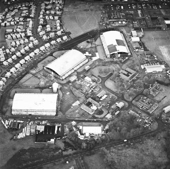 Oblique aerial view from ESE, centred on three hangars and various other buildings. The runway is visible in the top right-hand corner of the photograph.