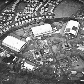 Oblique aerial view from NE, centred on three hangars and various other buildings. The runway is visible in the top right-hand corner of the photograph.