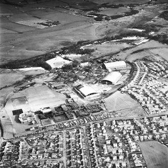 Oblique aerial view from WNW, centred on three hangars and various other buildings.