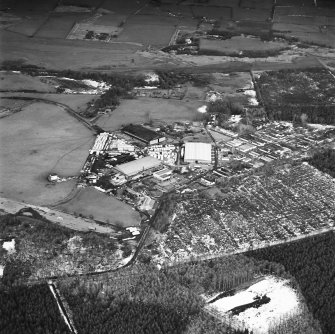 Oblique aerial view from WNW, centred on three hangars and various other buildings.