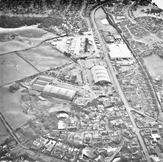 Oblique aerial view from NE, centred on hangars and various other buildings.