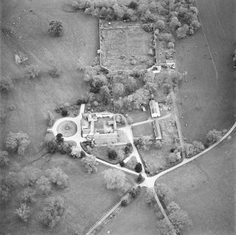 Oblique aerial view centred on the tower-house, stables and outbuildings, taken from the NNW.