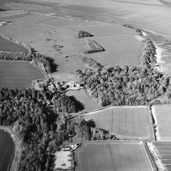 General oblique aerial view looking over cottage, country house, stables and gardens towards Tallowquhairn, taken from the SW.