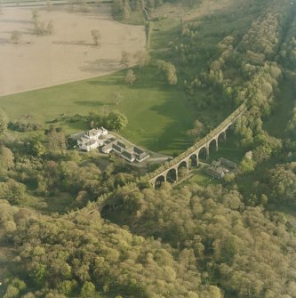 Oblique aerial view centred on the country house, railway viaduct and stables, taken from the NNW.