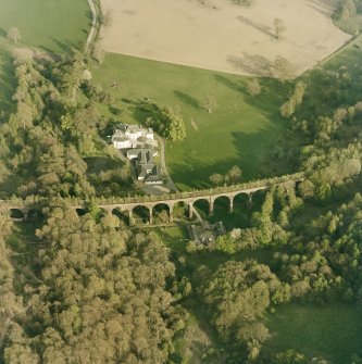 Oblique aerial view centred on the country house, railway viaduct and stables, taken from the NW.