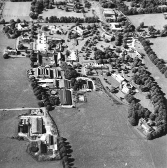 Oblique aerial view centred on the hospital and the church, taken from the SE.