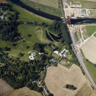 Oblique aerial view centred on the country house and garden with the lodge, railway viaduct and construction works adjacent, taken from the S.