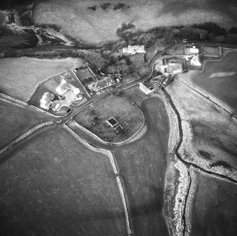 Oblique aerial view centred on church and burial ground from SE.