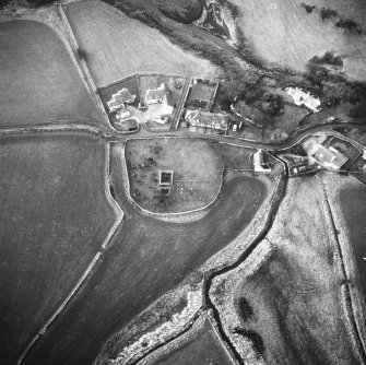 Oblique aerial view centred on church and burial ground from E.