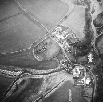 Oblique aerial view centred on church and burial ground from NE.